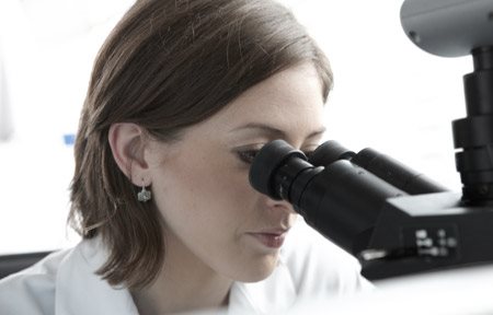 Científica mirando al microscopio